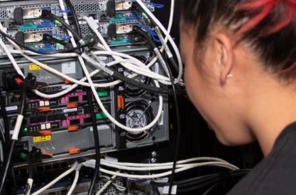 student examining exposed wires of a supercomputer