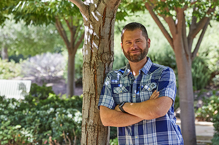 Jorge Escobar standing next to a tree, arms folded