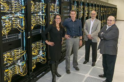 Group of three men and one woman in front of a computer system