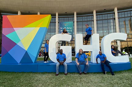 several people posed outside the 2019 conference venue on large GHC letters