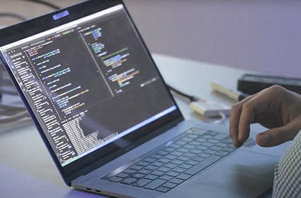 person working at a laptop whose screen is filed with code