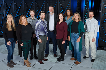 nine people stand as a group in front of the Sierra supercomputer