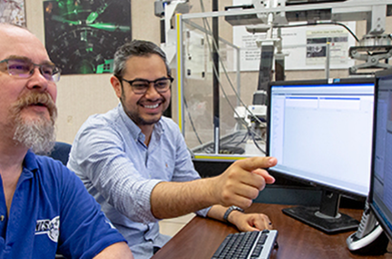 Jorge works with another person on a desktop computer