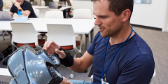 a participant in the hackathon room examines the DeepRacer car