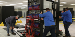 three people install an early access system rack in the machine room