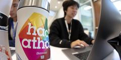 Summer interns work on their hackathon projects. A water bottle with a hackathon sticker on it is in the photo’s foreground.