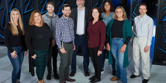 nine people stand as a group in front of the Sierra supercomputer